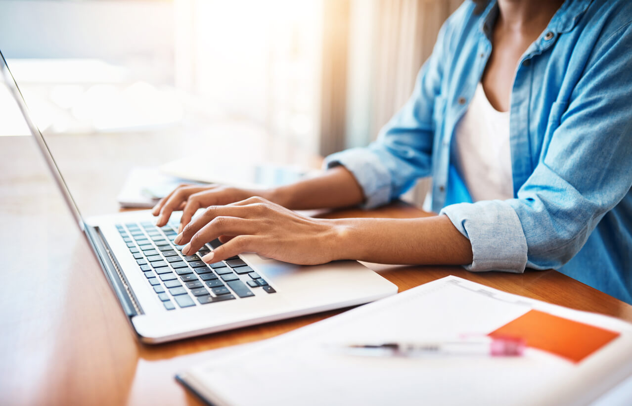 The woman is typing on the keyboard of the laptop